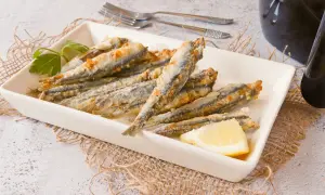 Boquerones en freidora de aire, dorados y crujientes, servidos en plato blanco con limón y perejil.
