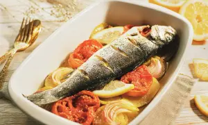 Lubina al horno con patatas, tomates y limón, lista para disfrutar.