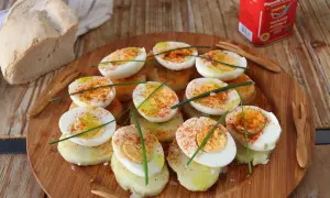 Deliciosos huevos a la gallega, cortados por la mitad y espolvoreados con pimentón, sobre rodajas de patata.