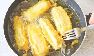 Soldaditos de pavia dorándose en aceite caliente. Un tenedor los voltea para una fritura perfecta.