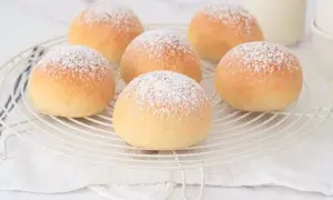 Seis deliciosas cocas de patata espolvoreadas con azúcar glas sobre una rejilla.