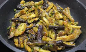 Berenjenas al ajillo salteadas en sartén, con trozos dorados y tiernos, salpicadas de ajo y perejil.