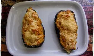 Dos berenjenas rellenas de gambas, gratinadas con queso, listas para disfrutar.