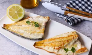 Dos filetes de dorada a la plancha, jugosos y dorados, servidos con perejil fresco y una rodaja de limón.