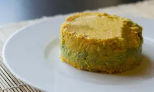 Pastel de calabacín, jamón y queso, con capas verdes y amarillas, servido en plato blanco.