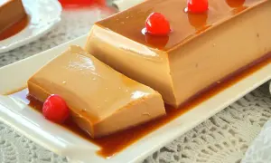 Un delicioso flan de café, con caramelo líquido y decorado con cerezas rojas, servido en un plato blanco.