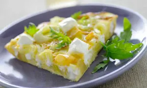 Porción de tortilla con puerros y queso de cabra, decorada con rúcula. Ideal para tus recetas con puerros.
