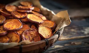 Rodajas de boniato al horno, crujientes y doradas, servidas en una cesta de mimbre.