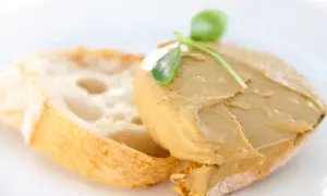 Tostada con paté de mejillones y una hoja verde como decoración.
