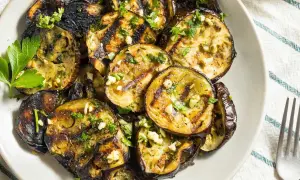 Rodajas de berenjena a la plancha, doradas y tiernas, con ajo picado y perejil fresco. Un plato delicioso y saludable.