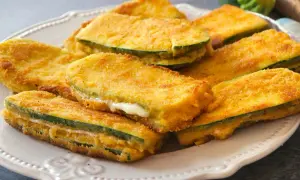 San jacobos de calabacín dorados y crujientes, rellenos de queso fundido, servidos en un plato blanco.