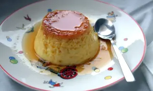 Delicioso flan de huevo casero, la receta de la abuela que nunca falla. Servido en un plato con dibujos infantiles y una cuchara lista para disfrutar.