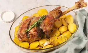 Pierna de cordero al horno con patatas doradas, ajo y romero. Un plato principal jugoso y aromático.
