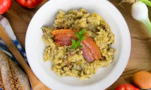 Un plato de trinxat de montaña con crujiente panceta y perejil. Acompañado de pan rústico, tomates y cebolletas.