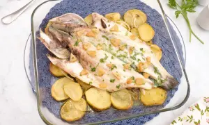Lubina al horno con patatas y ajo, recién salida del horno, lista para servir.