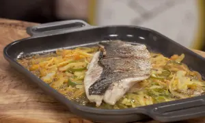 Filete de corvina a la roteña, con verduras salteadas en una sartén de hierro fundido.