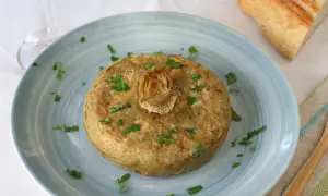 Tortilla de patatas con alcachofas de bote, decorada con perejil. Ideal para tus recetas con alcachofas de bote.