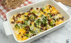 Delicioso brocoli al horno gratinado con queso y tocino crujiente, servido en una fuente blanca.