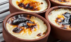 Cuatro cazuelas de barro con tarta de arroz horneada, con una capa superior dorada y caramelizada.