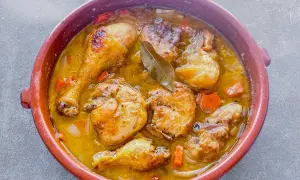 Delicioso pollo de corral guisado en cazuela de barro con zanahorias y laurel.