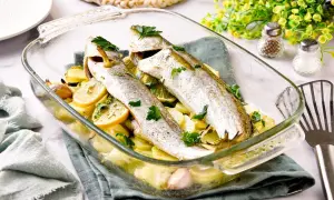 Pescadilla al horno con patatas, limón y ajo, recién salida del horno.