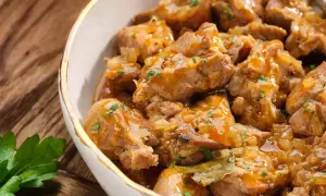 Un delicioso plato de caldereta de cordero, con trozos tiernos de carne en una salsa dorada y aromática, adornado con perejil fresco.