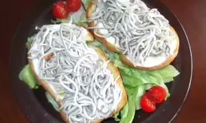 Dos tostas de gulas sobre lechuga y tomate cherry, un bocado delicioso.