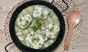 Merluza a la vasca, un plato tradicional con trozos de pescado blanco en una salsa cremosa con almejas y perejil picado.