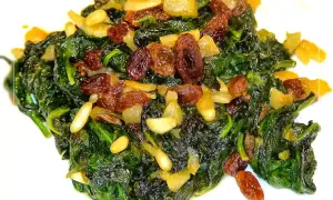 Espinacas a la catalana, un plato vibrante con espinacas salteadas, pasas dulces y piñones tostados.