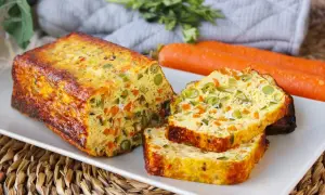 Pastel de verduras casero, con trozos visibles de zanahoria y guisantes, servido en una bandeja blanca.