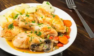 Sabroso pollo a la pepitoria con patatas, zanahorias, guisantes y champiñones, todo espolvoreado con perejil fresco.