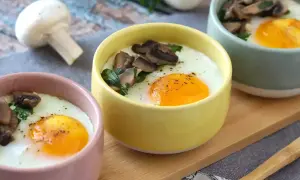 Deliciosos huevos al horno con champiñones y perejil, servidos en coloridas tazas. Un desayuno perfecto.
