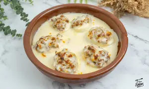 Huevos rellenos gratinados con bechamel y queso, servidos en una cazuela de barro.
