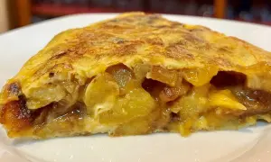 Un trozo jugoso de tortilla de patatas, con patatas tiernas y huevo dorado, servido en un plato blanco.