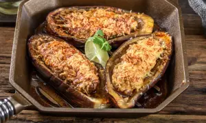Berenjenas rellenas airfryer doradas y gratinadas, servidas en una sartén de hierro fundido con una rodaja de lima.