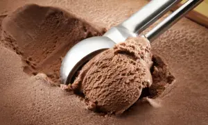 Cuchara saca una porción generosa de helado de chocolate casero, con textura cremosa y color intenso.
