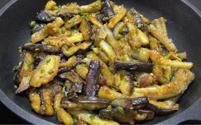 Berenjenas al ajillo salteadas en sartén, con trozos dorados y tiernos, salpicadas de ajo y perejil.