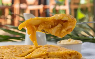 Un tenedor levanta un trozo jugoso de pincho de tortilla, mostrando su interior de patatas y huevo.