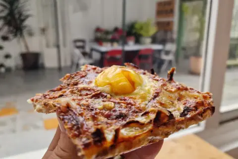 Deliciosa coca de cebolla con huevo frito coronando esta maravilla. Perfecta para un aperitivo o cena rápida.