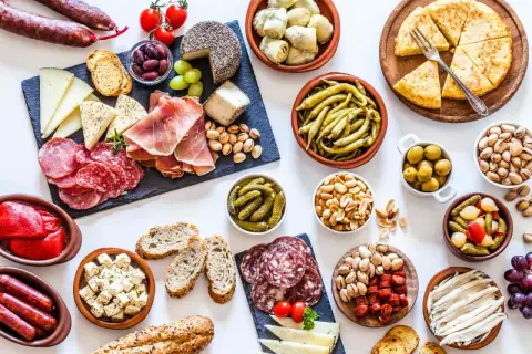 Gran variedad de aperitivos baratos para mucha gente: embutidos, quesos, aceitunas, frutos secos, pimientos, boquerones y tortilla.