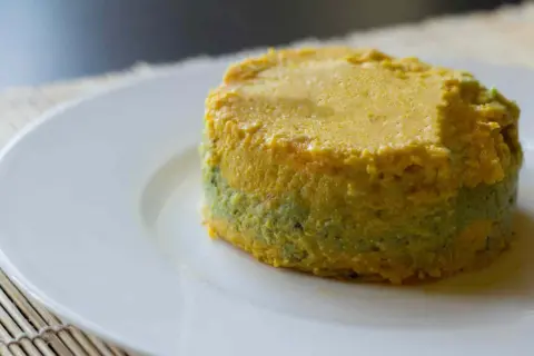 Pastel de calabacín, jamón y queso, con capas verdes y amarillas, servido en plato blanco.