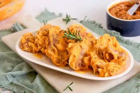 Delicioso lomo en manteca, servido en plato blanco con romero. Un manjar cremoso y apetitoso.