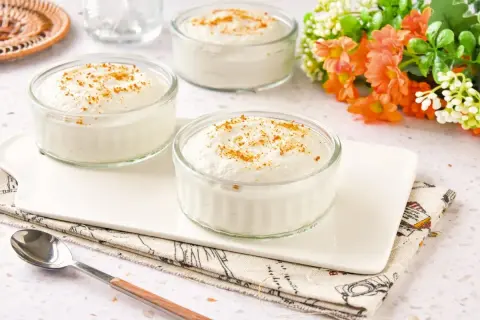 Delicioso mousse de yogur en vasitos de cristal, espolvoreado con canela. Un postre ligero y refrescante.