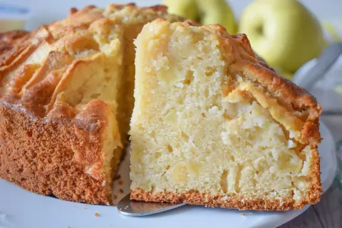 Un trozo de bizcocho de manzana casero, con trozos de fruta visibles en su interior tierno y dorado.