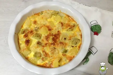 Tortilla dorada con trozos de puerros al horno y queso gratinado, lista para disfrutar.