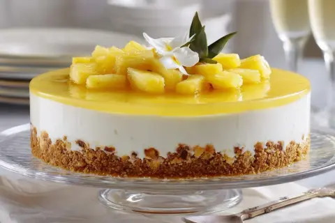 Deliciosa tarta de piña con trozos de fruta fresca y una capa de gelatina brillante, sobre una base crujiente.