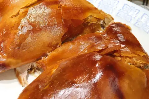 Un crujiente cochinillo al horno, con piel dorada y carne jugosa, listo para ser disfrutado en una celebración.