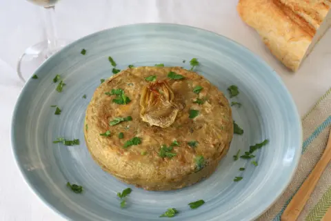Tortilla de patatas con alcachofas de bote, decorada con perejil. Ideal para tus recetas con alcachofas de bote.