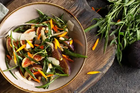 Ensalada gourmet con higos frescos, rúcula, piñones y láminas de queso. Perfecta para tus recetas con higos frescos.
