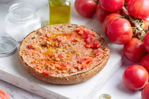 Rebanada de pan tostado con tomate rallado y aceite de oliva, lista para disfrutar de un delicioso pa amb tomàquet.